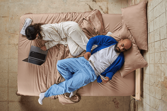 Stel in bed met bamboelakens overdag, comfort in alle seizoenen demonstrated.