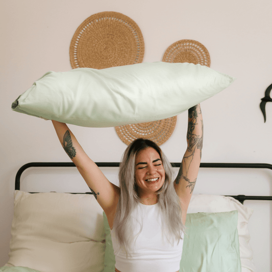 Vrouw met witte comfortabele bamboe beddengoed op een bed