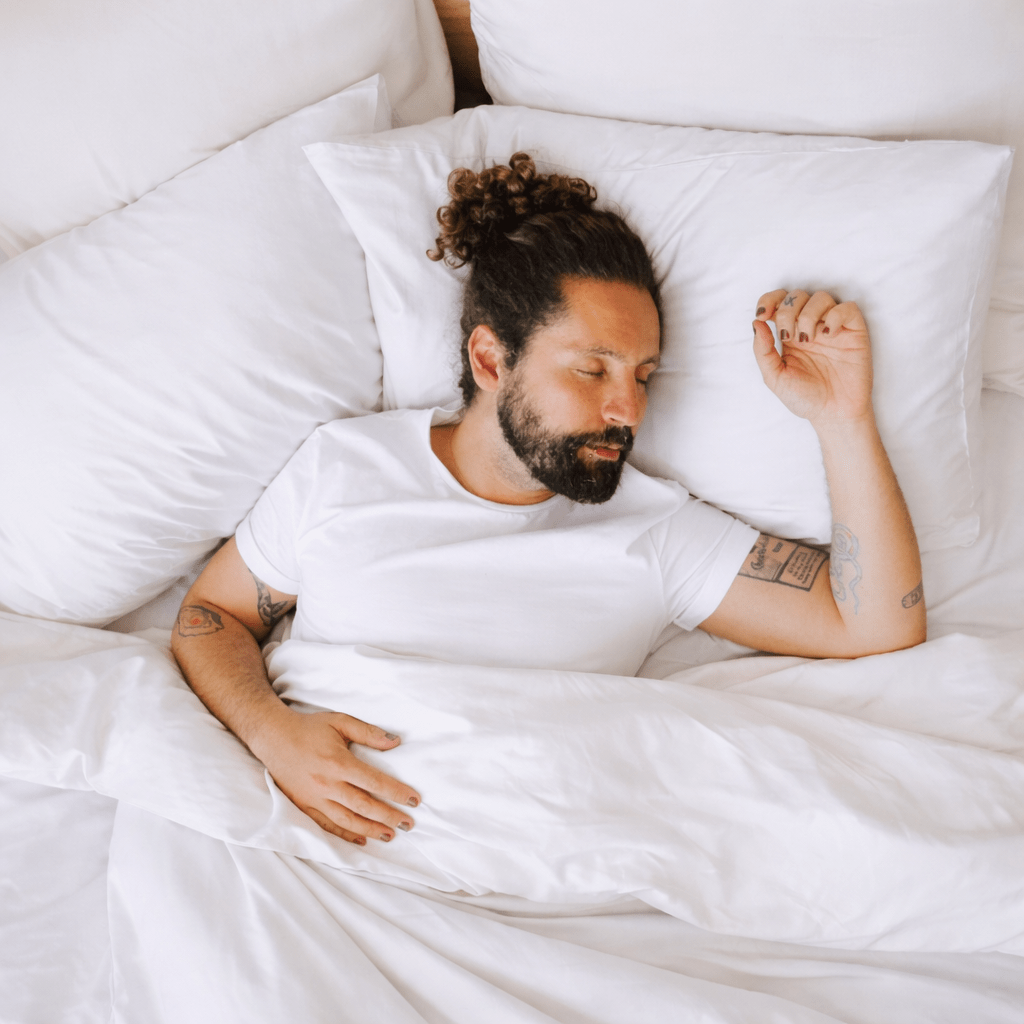 Homme dormant confortablement sur des draps en bambou blanc hypoallergénique