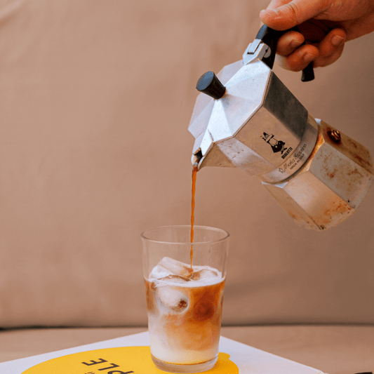 Hete moka wordt in een beker met ijs op beige achtergrond gegoten.