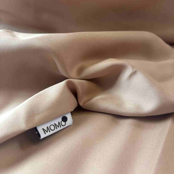 Drap housse bambou beige plié avec étiquette momo-cotton visible, texture douce et chute du tissu