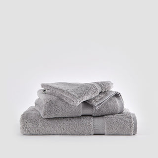 Ensemble de serviettes en bambou gris empilées sur fond blanc, incluant serviettes de visage, main et bain