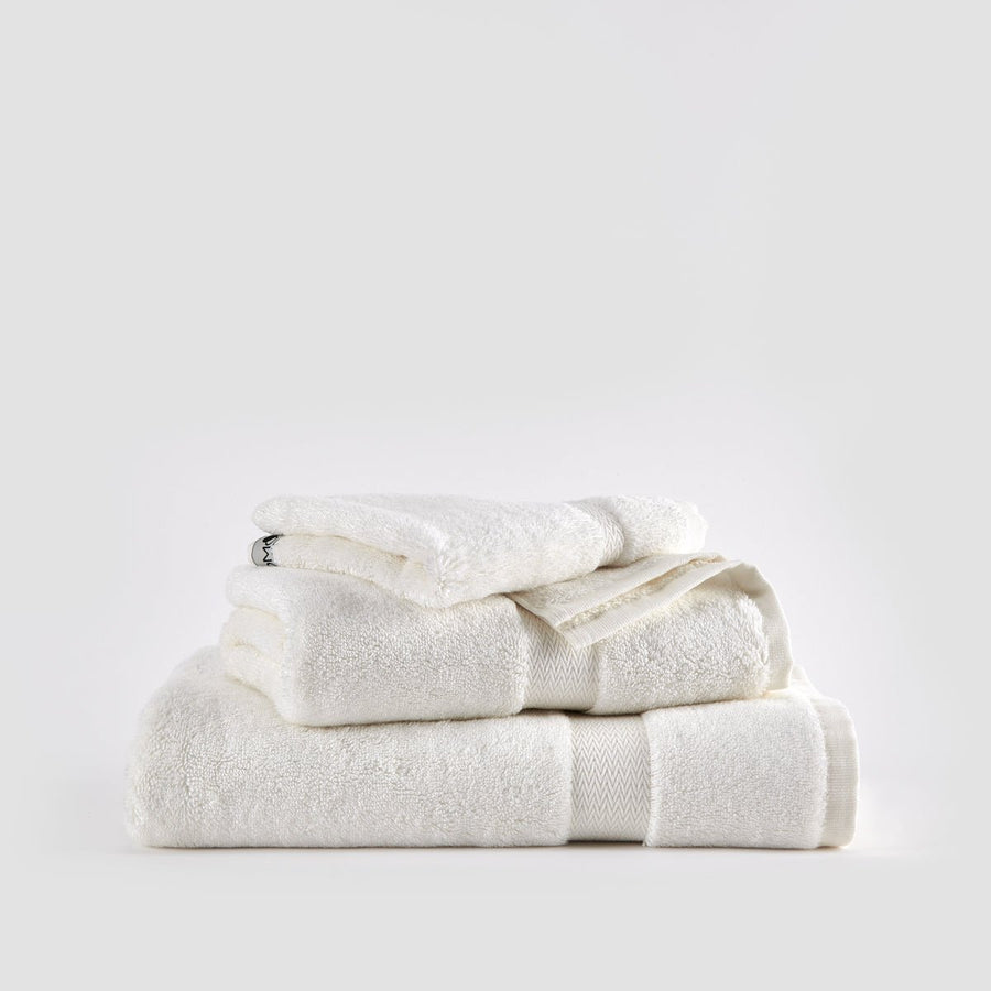 Ensemble de serviettes en bambou blanc empilées avec serviettes de visage, main et bain sur fond neutre