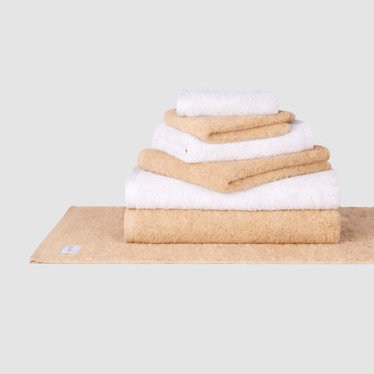 Stacked beige and white cotton towel set by Momo Cotton displayed on neutral background