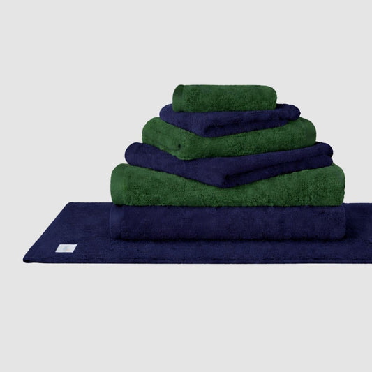 Ensemble de serviettes Wabi Sabi superposées bleu marine et vert de Momo Cotton sur fond neutre