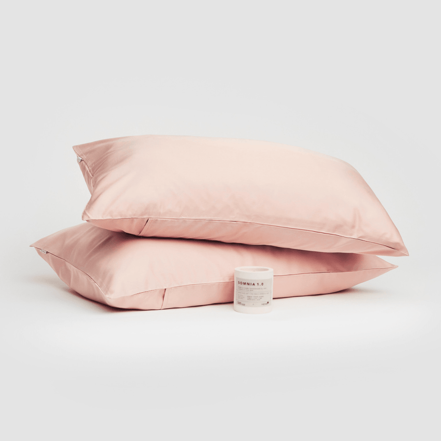 Paire de taies d'oreiller en coton rose présentées avec le produit Somnia 1.0 sur fond blanc