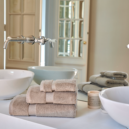 Ensemble de serviettes en bambou Alba empilées sur un lavabo de salle de bain élégante et moderne