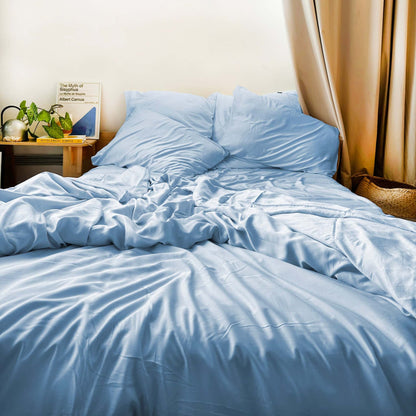 Messy bed with blue bamboe lakens en kussens – zacht, ademend en duurzaam beddengoed