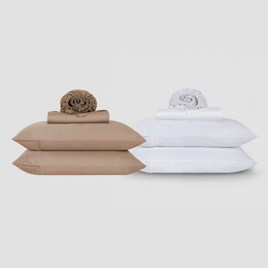 Beige and white cotton sheet sets stacked with rolled linens and comforters displayed on neutral background