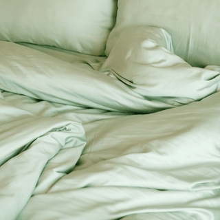 Bamboo bedding set in sage green displayed on bed showing fitted sheet, flat sheet, pillowcase and duvet cover